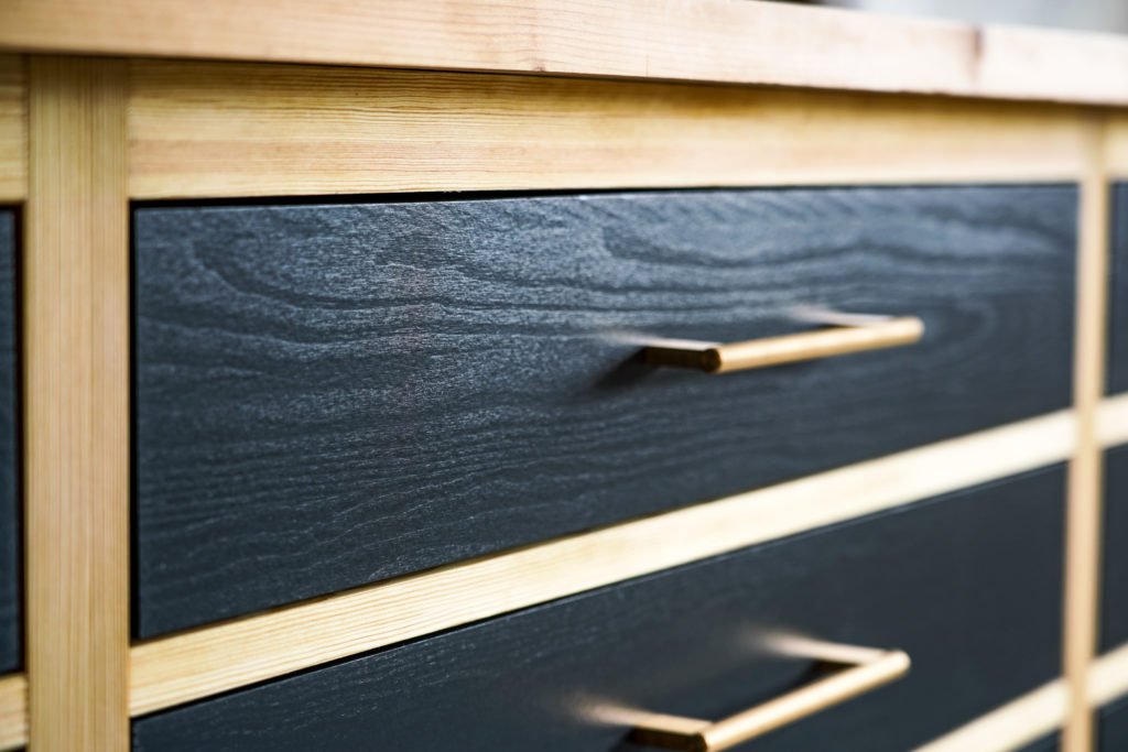 Närbild av lådfront i mörk kulör med trädetalj