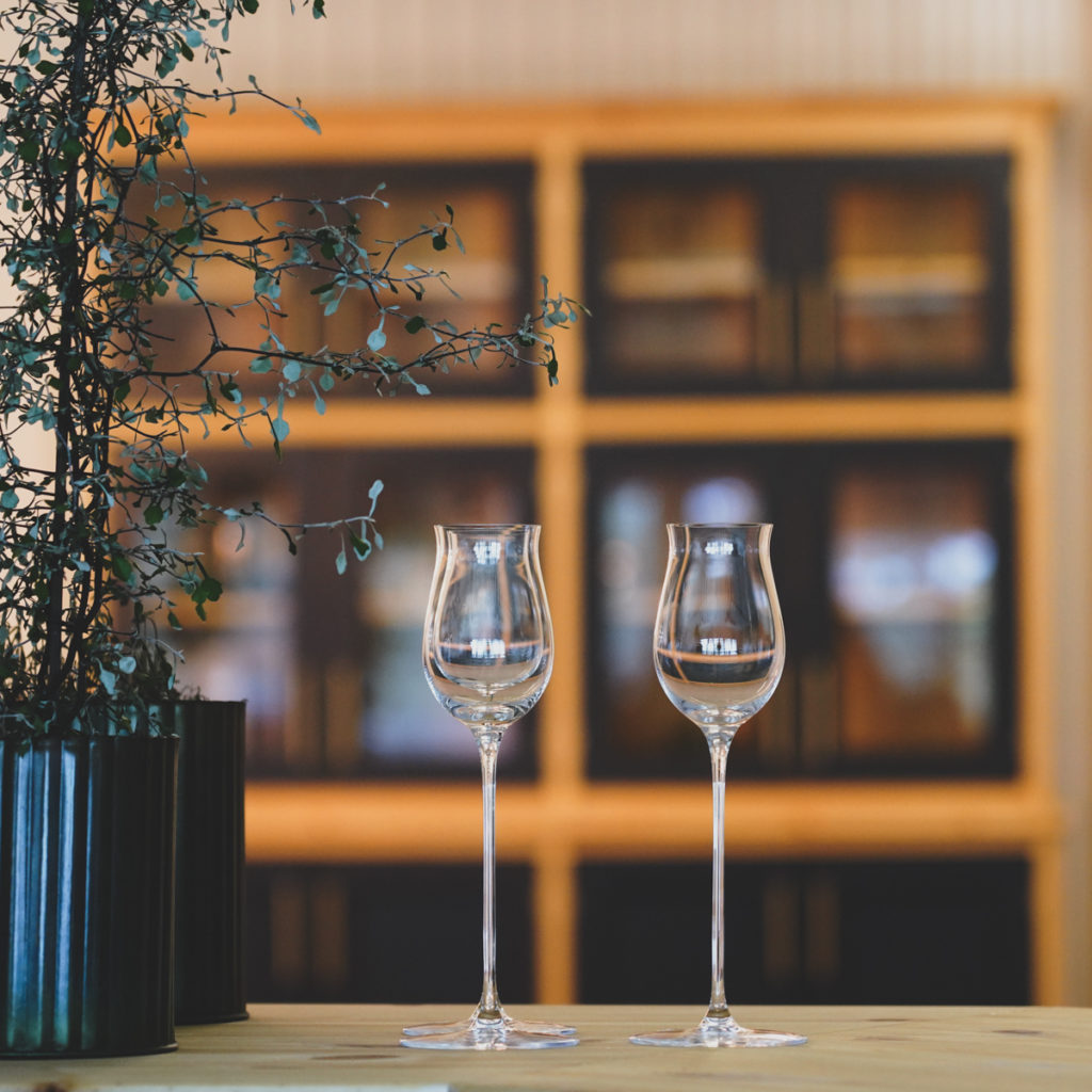 Glas på bord med vitrinskåp i bakgrunden