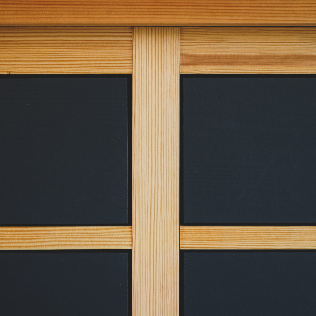 Närbild av skåpsluckor med träinfattning och mörk panel