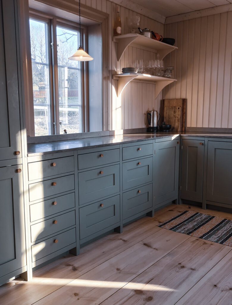 Gråblått kök med lång bänkrad och fönster