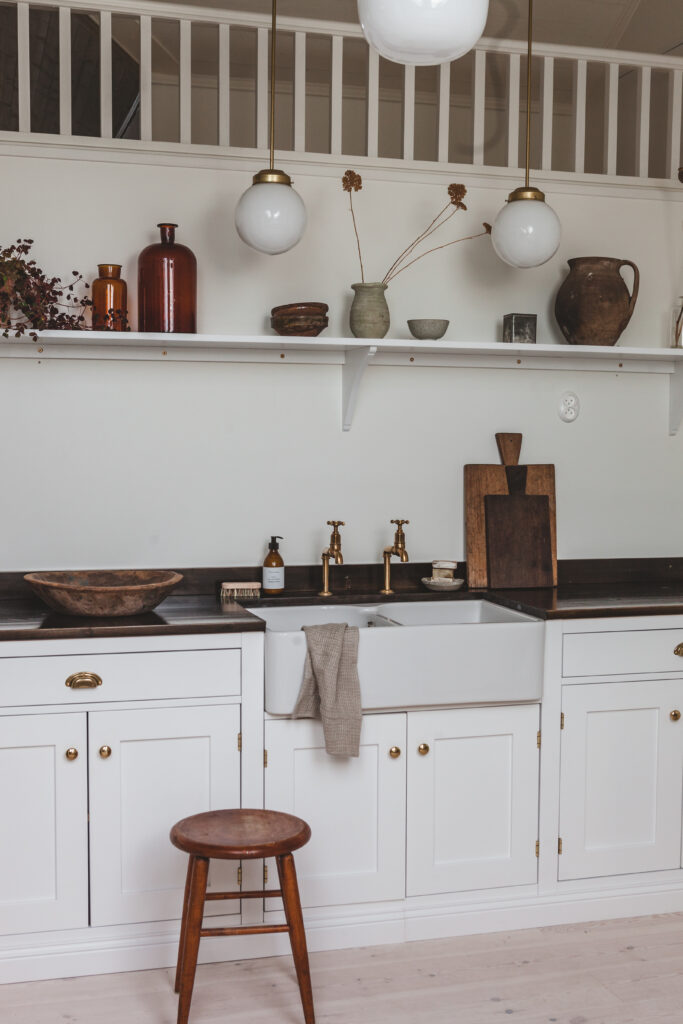 Diskho och bänkskiva i vitt kök med mässingsblandare