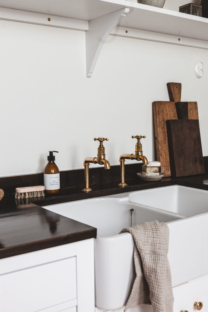 Närbild av diskho med mässingsblandare och mörk bänkskiva