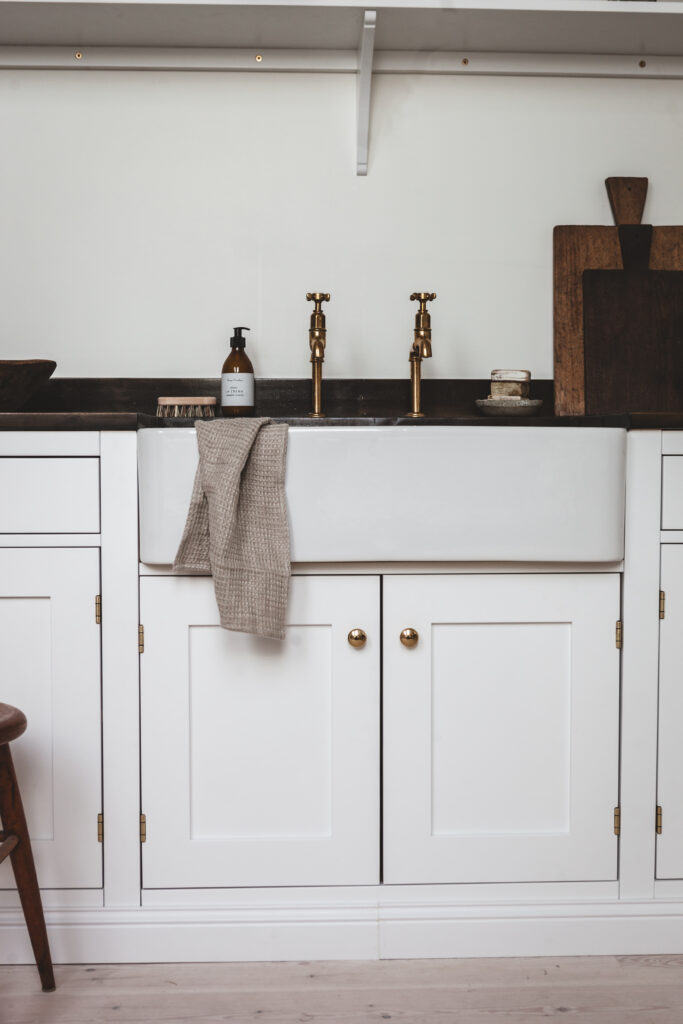 Underskåp i vitt kök med mörk bänkskiva och handduk