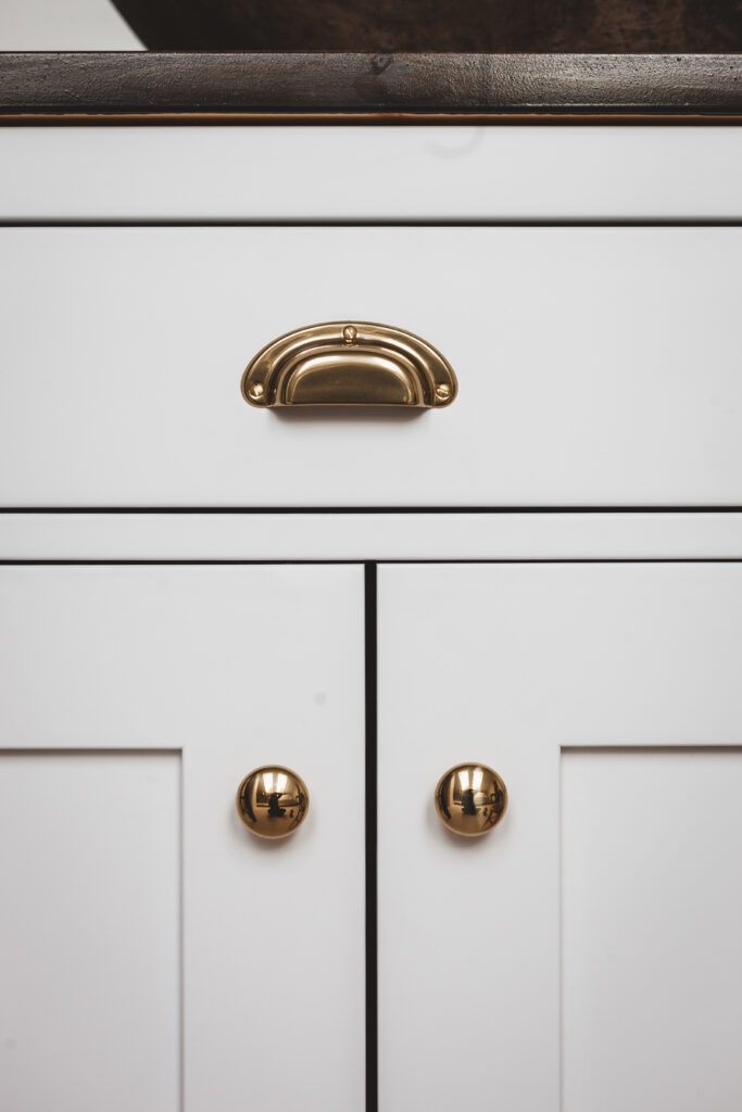 Vit kökslucka med mässingsknopp i närbild