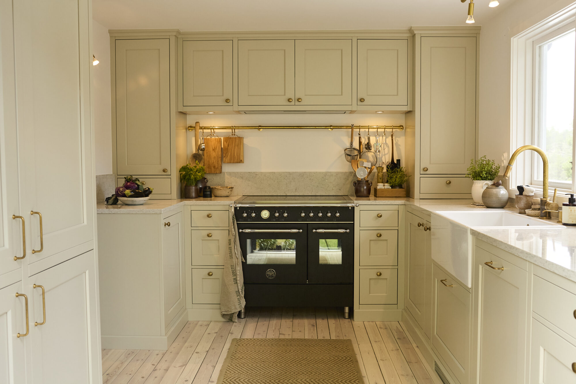 Ljust kök med svart spis och bänkskiva i vinkel