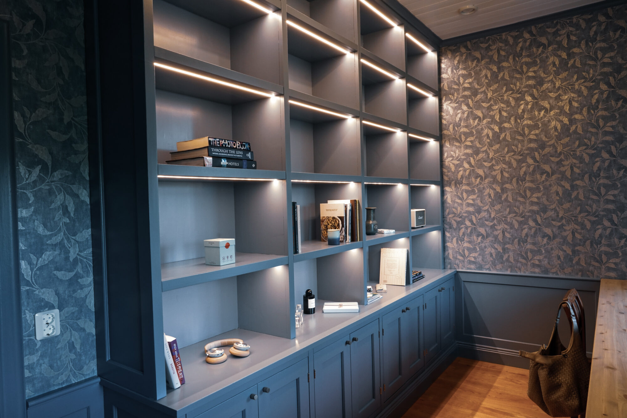 Hörnsektion av blå bokhylla med integrerad belysning