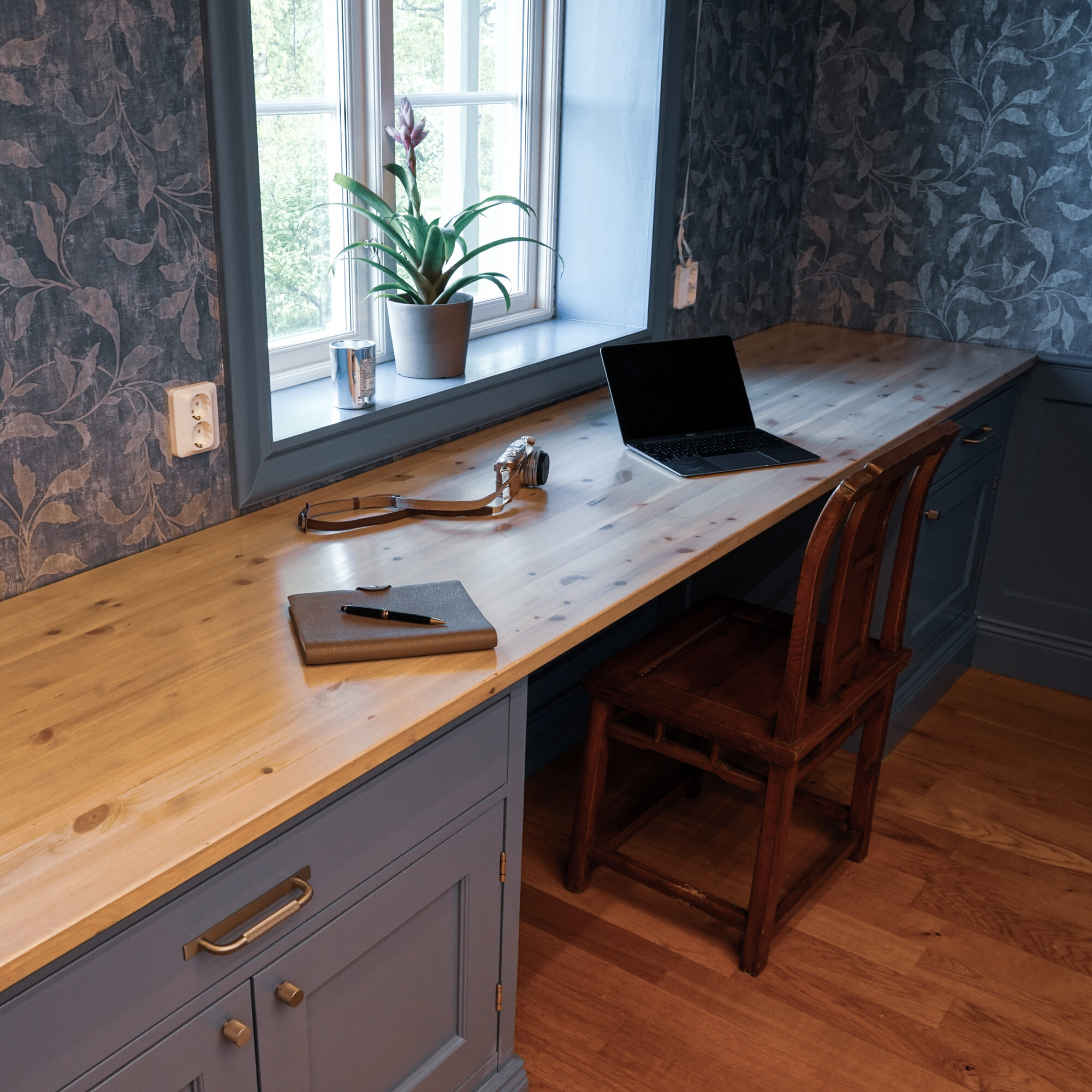 Skrivbord i massiv träskiva vid fönster i blått rum