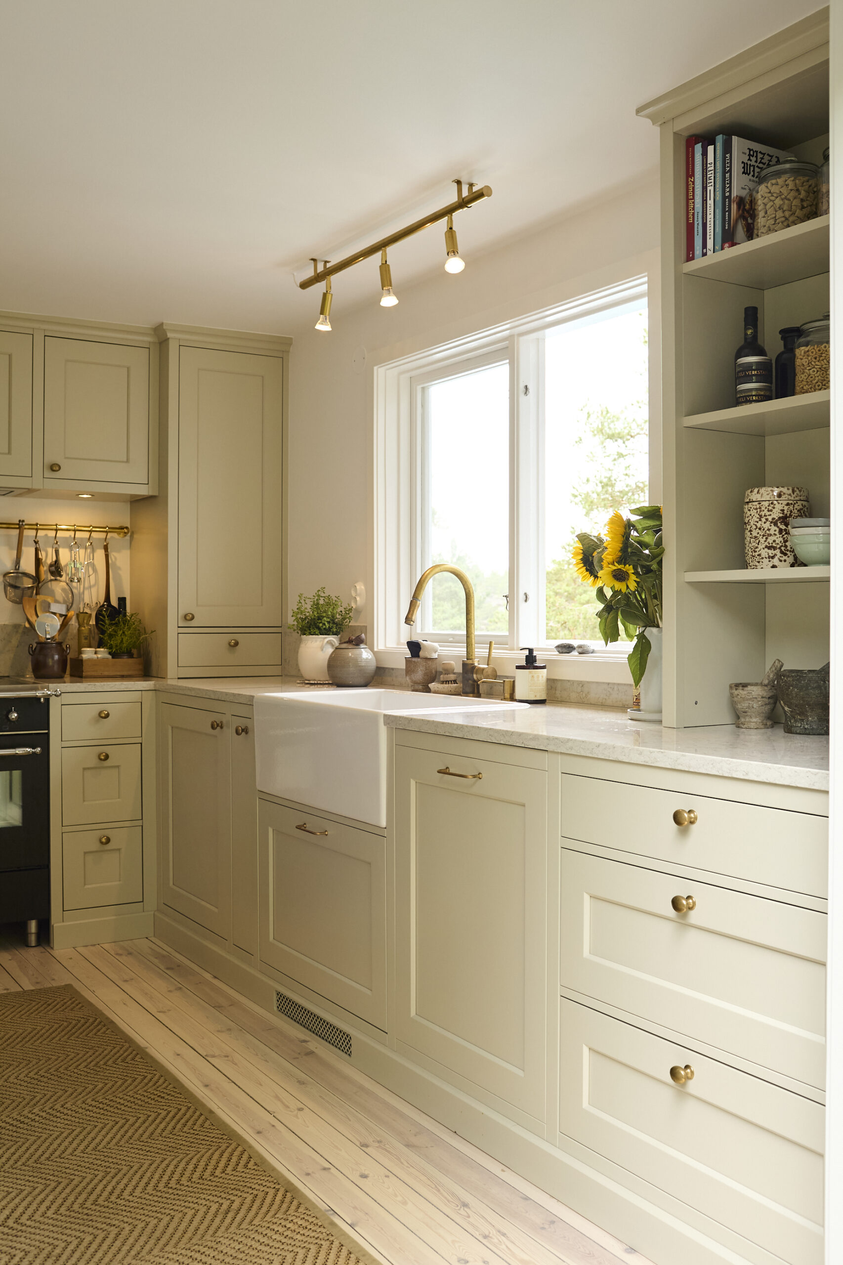 Diskbänk vid fönster i ljust platsbyggt kök