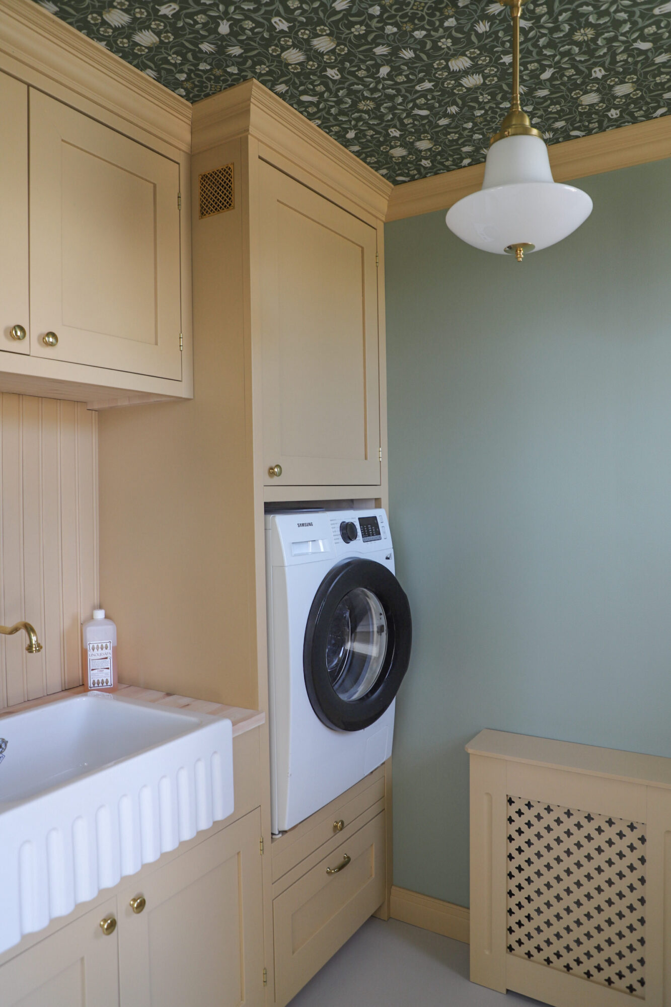 Tvättstuga med tvättmaskin och skåp i gul ton