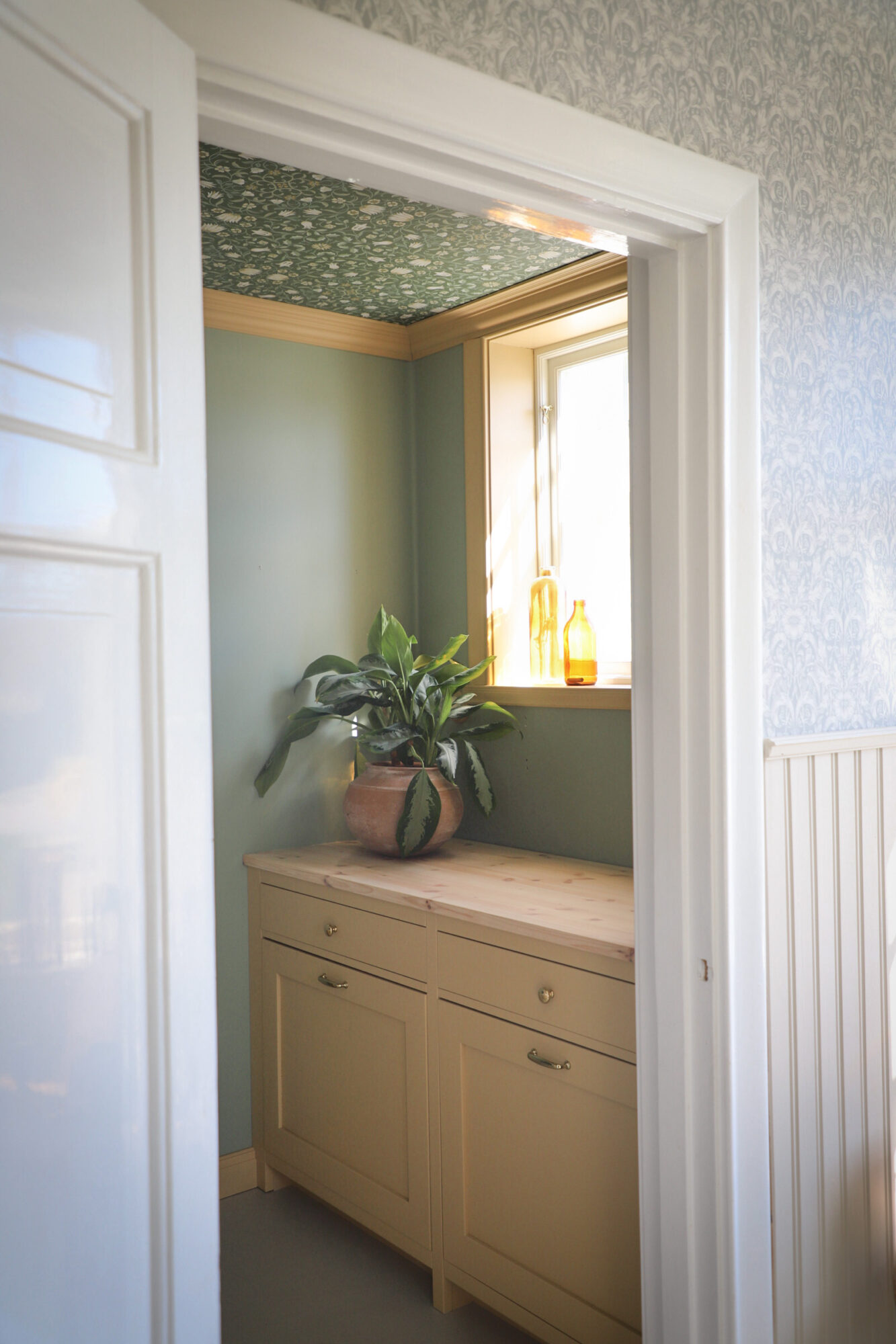 Gul tvättstuga med skåp och vägg i grönton