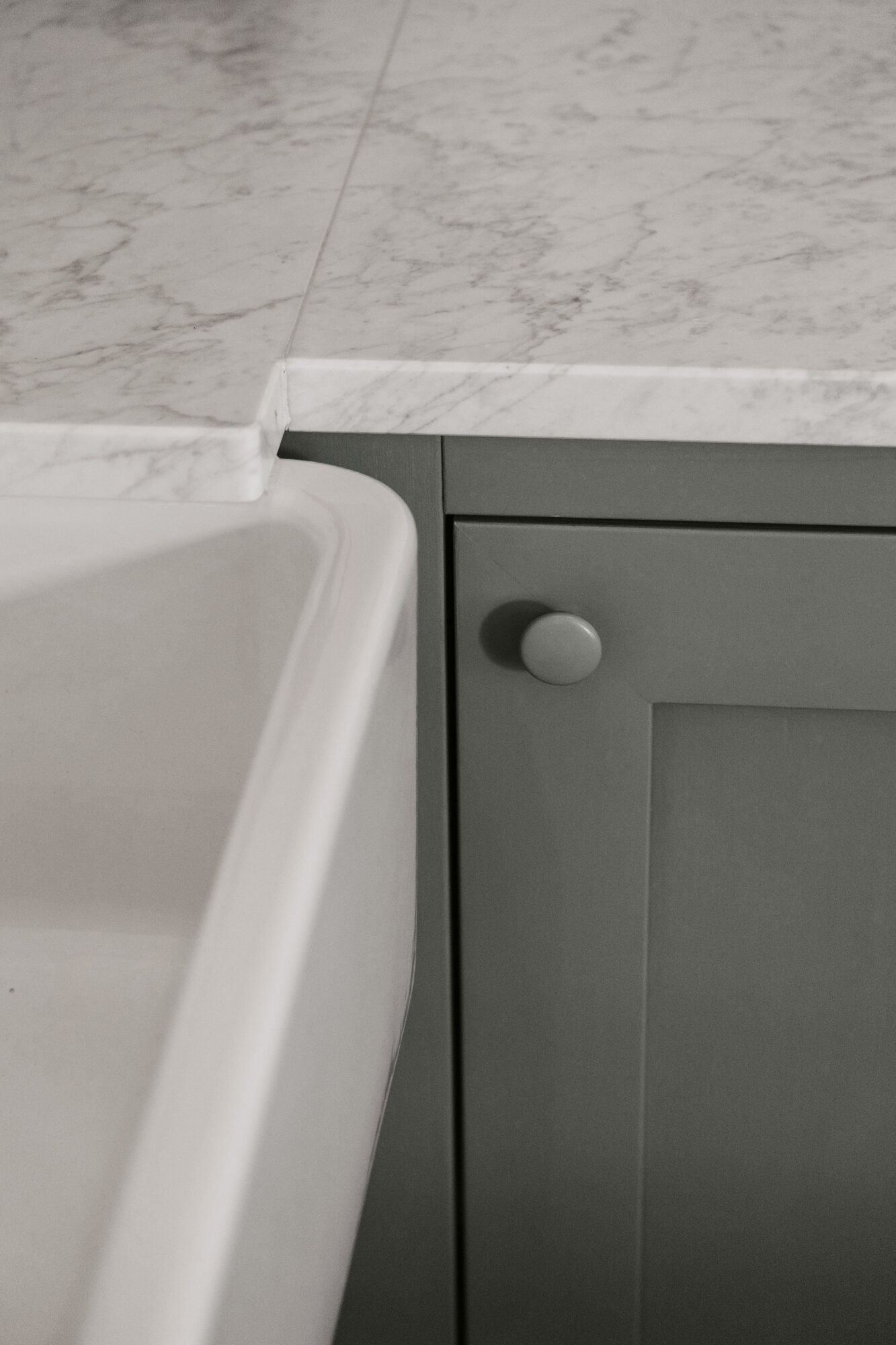 Detalj av kök i massivt trä med marmorbänkskiva och porslinsdiskho